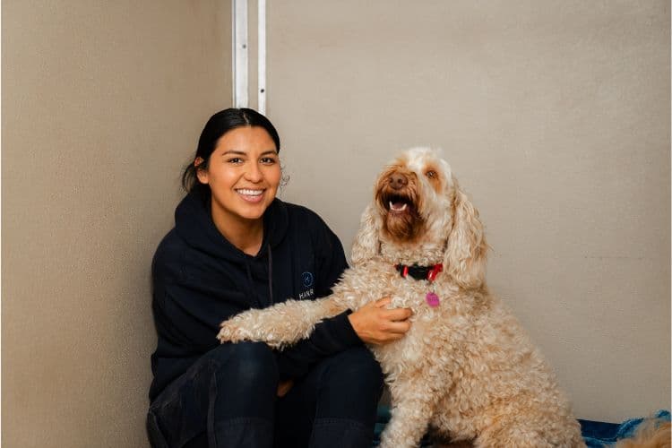 Hanrob Pet Hotels staff sitting with a goldendoodle